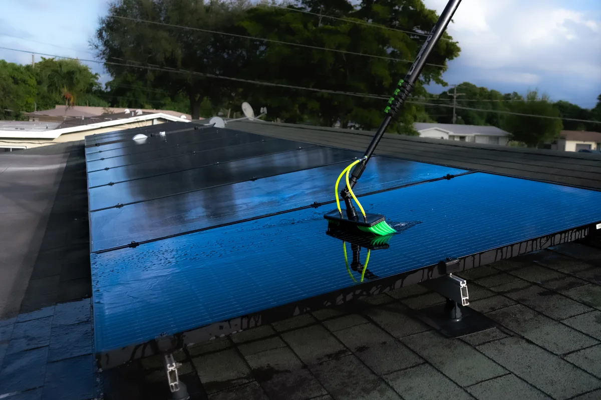 Soft-bristle pole cleaning a rooftop solar array in South Florida